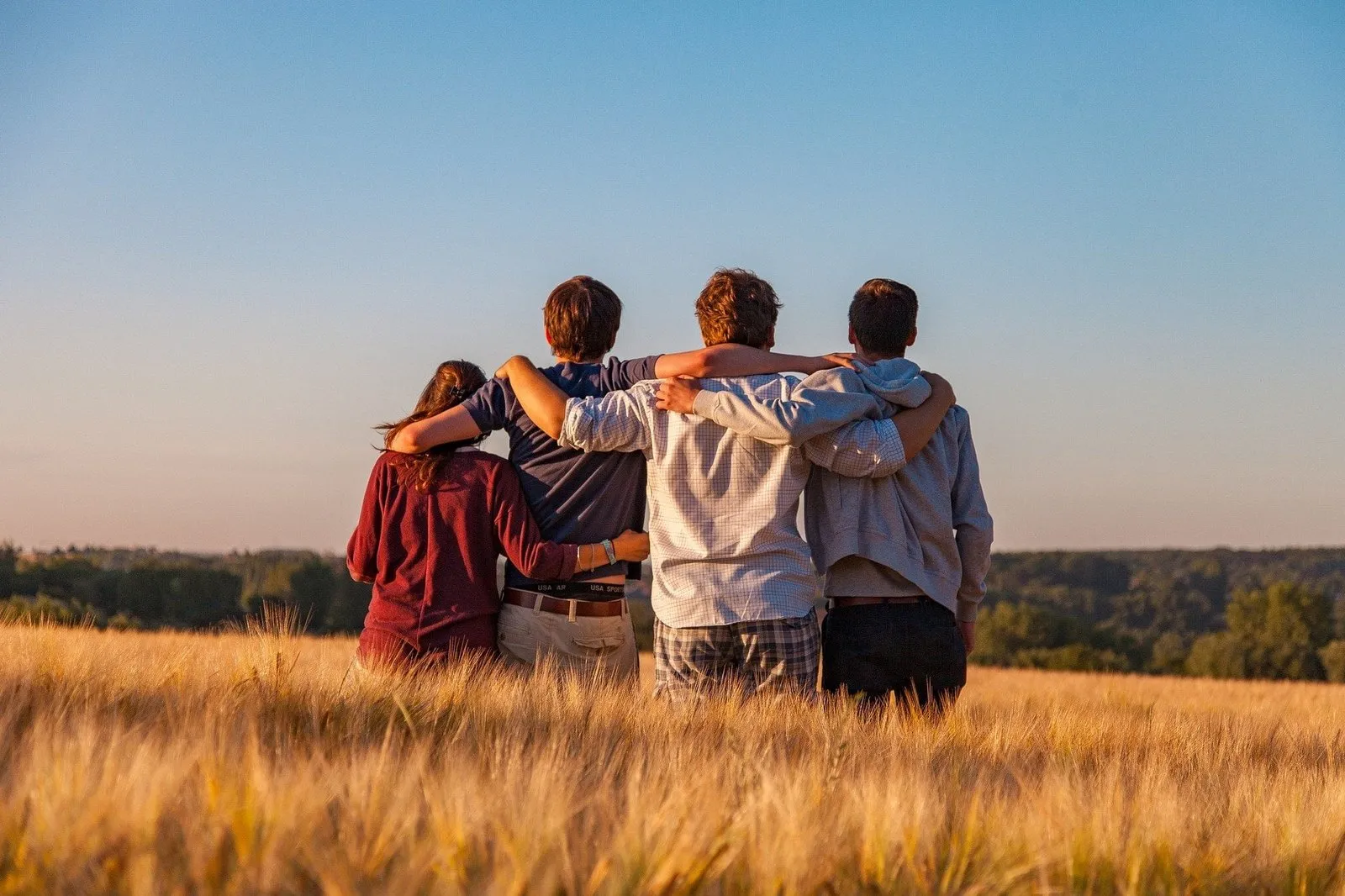 Four friends, arms around each other, looking out at the sky