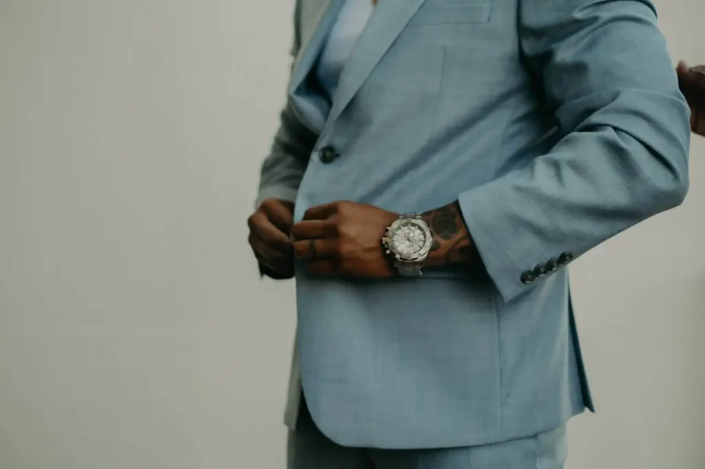 A man in a tailored suit adjusting his cuff